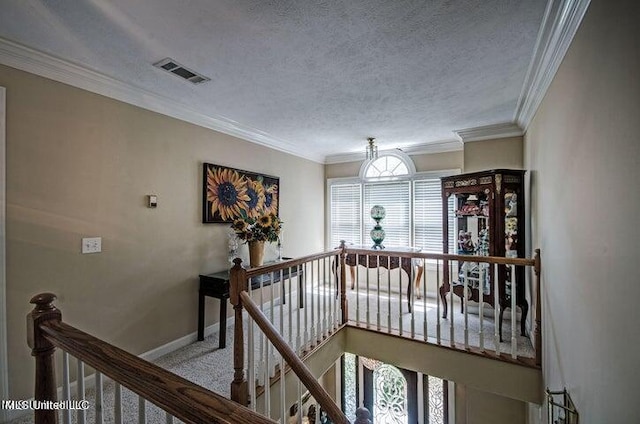 hallway featuring a textured ceiling, an upstairs landing, visible vents, baseboards, and carpet floors