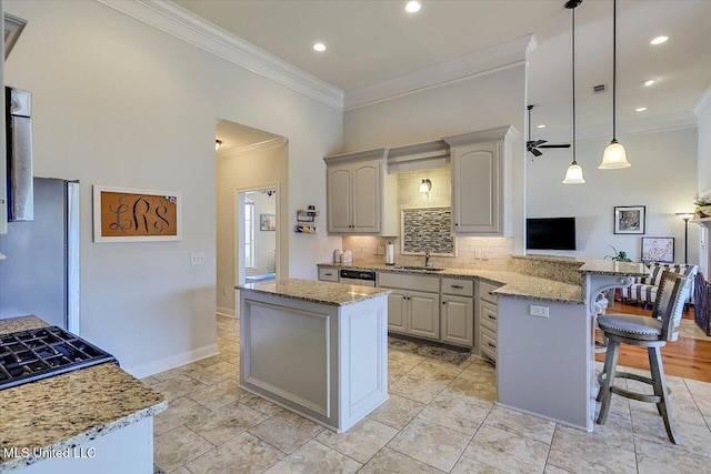 kitchen with a peninsula, ornamental molding, backsplash, and a sink