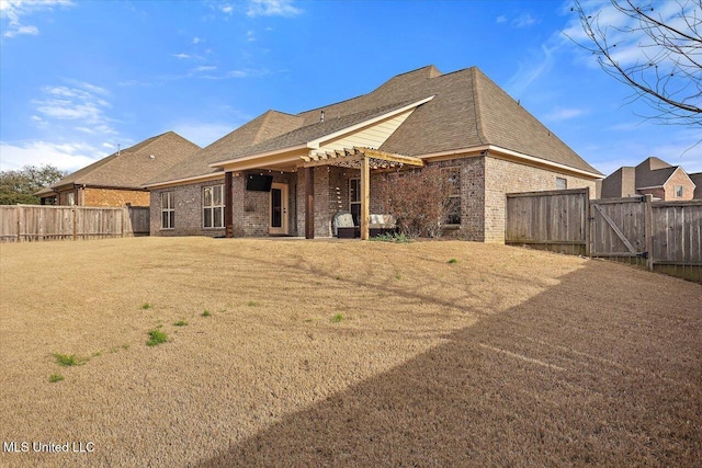 back of property with a gate, brick siding, fence, and a lawn