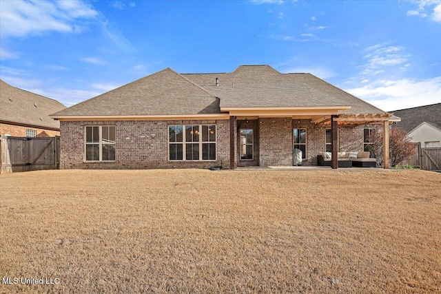 rear view of property featuring a yard, brick siding, outdoor lounge area, and a fenced backyard