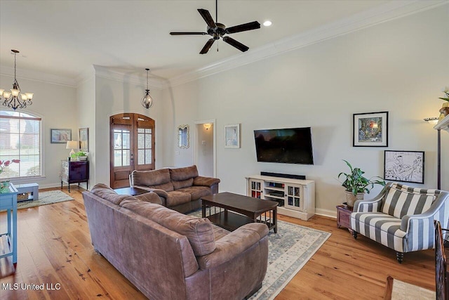 living room with baseboards, arched walkways, ornamental molding, french doors, and light wood-type flooring