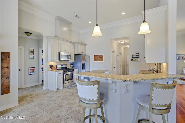 kitchen featuring ornamental molding, appliances with stainless steel finishes, a kitchen bar, and decorative backsplash