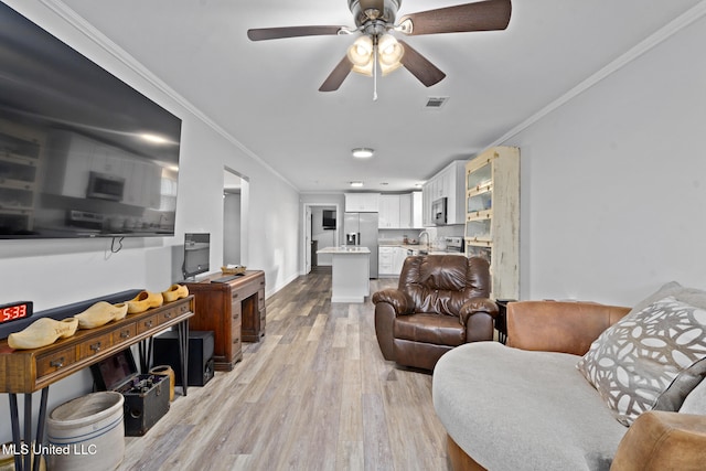 living room featuring sink, ceiling fan, crown molding, and light hardwood / wood-style flooring