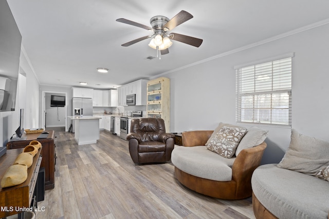 living room with sink, light wood-type flooring, ceiling fan, and crown molding