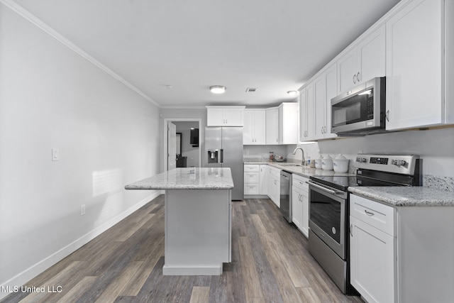 kitchen featuring appliances with stainless steel finishes, light stone counters, a kitchen island, white cabinets, and sink