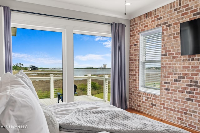 bedroom with multiple windows, hardwood / wood-style flooring, and brick wall