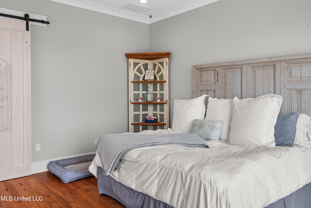 bedroom featuring ornamental molding, a barn door, and dark wood-type flooring