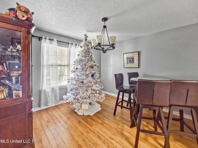11295 Peyton Dr, Gulfport, MS 39503 - dining space with a chandelier, a textured ceiling, wood finished floors, and baseboards