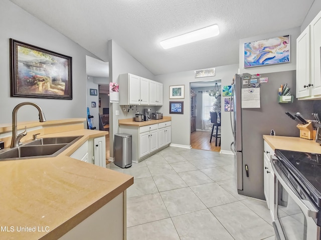 11295 Peyton Dr, Gulfport, MS 39503 - kitchen featuring a sink, stainless steel range with electric cooktop, lofted ceiling, white cabinets, and a textured ceiling