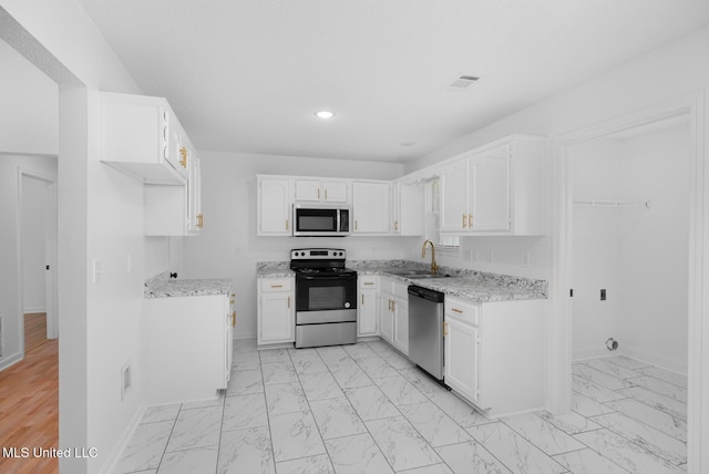 kitchen featuring baseboards, marble finish floor, appliances with stainless steel finishes, and a sink