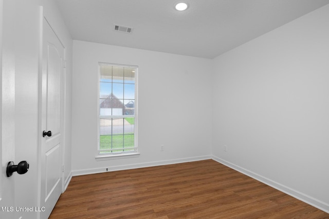 spare room with baseboards, visible vents, and wood finished floors