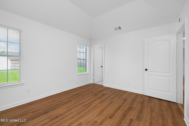 unfurnished room with vaulted ceiling, baseboards, visible vents, and wood finished floors