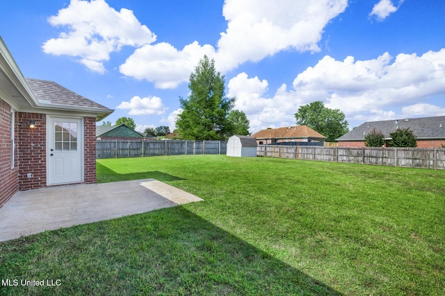 view of yard with a fenced backyard, a patio area, a storage unit, and an outbuilding