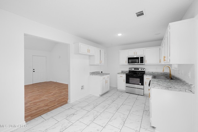 kitchen with a sink, marble finish floor, recessed lighting, white cabinets, and appliances with stainless steel finishes