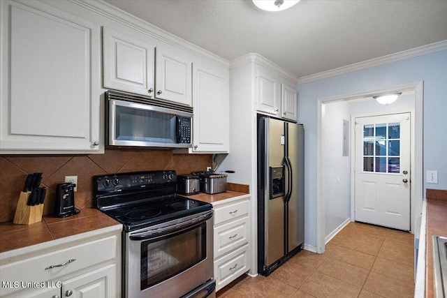 900 Redwood Cv, Byram, MS 39272 - kitchen with appliances with stainless steel finishes, decorative backsplash, white cabinetry, crown molding, and light tile patterned floors