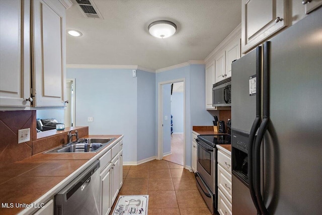 900 Redwood Cv, Byram, MS 39272 - kitchen with stainless steel appliances, white cabinets, ornamental molding, tile countertops, and light tile patterned floors
