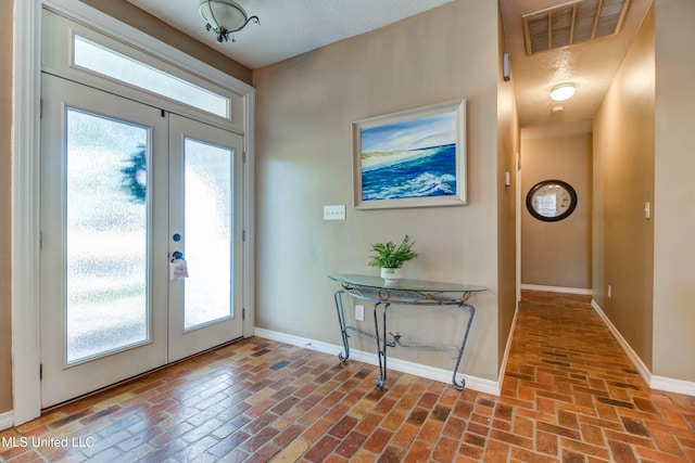 foyer with a textured ceiling, french doors, and plenty of natural light