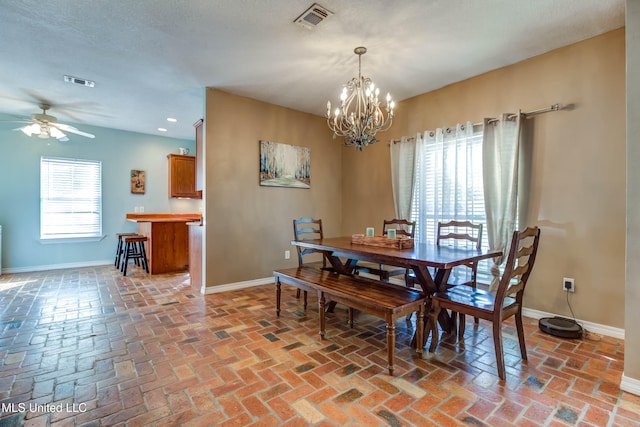 dining space featuring a textured ceiling and ceiling fan with notable chandelier