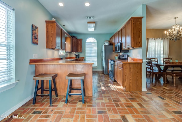 kitchen featuring kitchen peninsula, a kitchen bar, stainless steel appliances, and a wealth of natural light