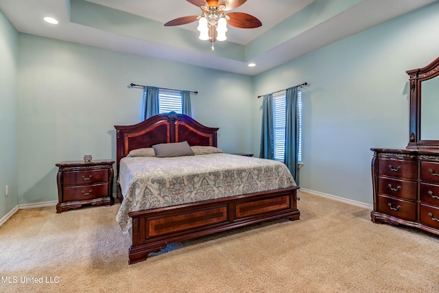 carpeted bedroom featuring a tray ceiling and ceiling fan