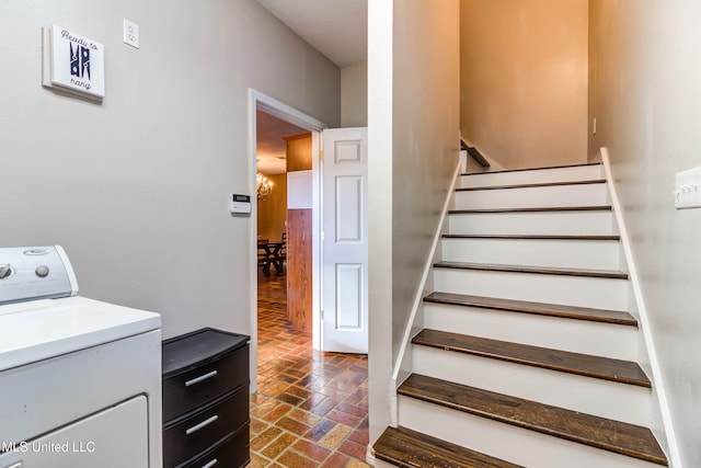 stairs featuring washer / clothes dryer and a chandelier