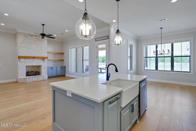 kitchen featuring visible vents, gray cabinetry, stainless steel dishwasher, open floor plan, and a sink