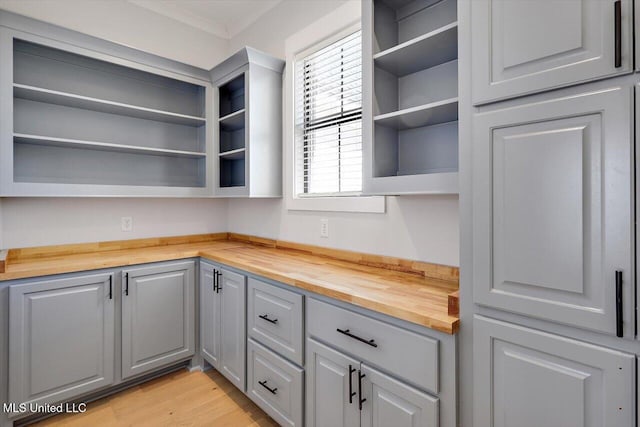 kitchen featuring butcher block countertops, light wood-style flooring, gray cabinetry, and open shelves