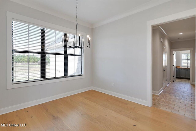 unfurnished dining area featuring light wood finished floors, a notable chandelier, baseboards, and crown molding