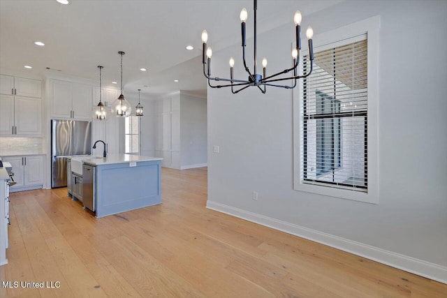 kitchen with baseboards, light countertops, stainless steel appliances, light wood-style floors, and white cabinetry