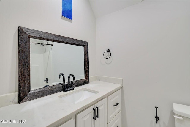 bathroom with toilet, vaulted ceiling, and vanity