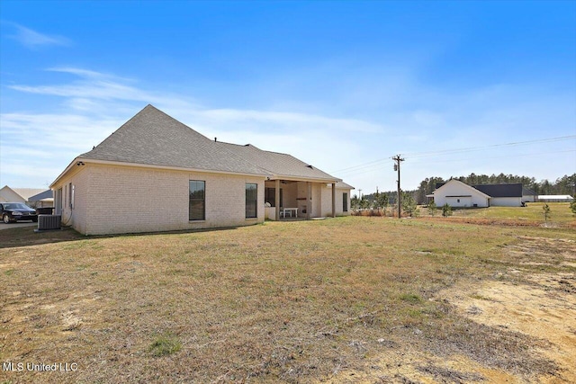 back of property featuring central AC, brick siding, and a lawn