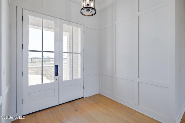 doorway to outside with french doors, a decorative wall, and light wood finished floors