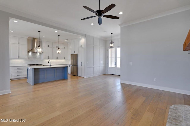 kitchen with tasteful backsplash, freestanding refrigerator, open floor plan, white cabinets, and wall chimney range hood