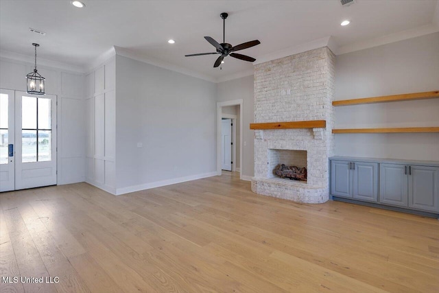 unfurnished living room featuring crown molding, recessed lighting, a large fireplace, light wood-type flooring, and baseboards