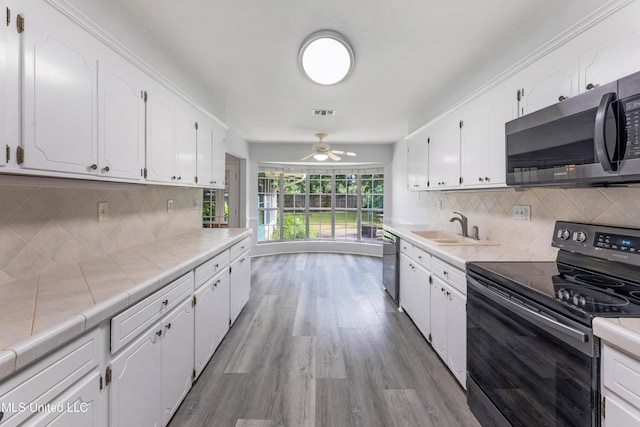 4 Briarwood Cir, Long Beach, MS 39560 - kitchen with stainless steel appliances, tile counters, white cabinetry, light wood finished floors, and ceiling fan