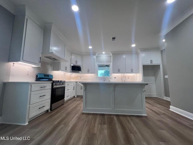 kitchen with stainless steel appliances, dark wood-type flooring, wall chimney range hood, a center island, and white cabinetry