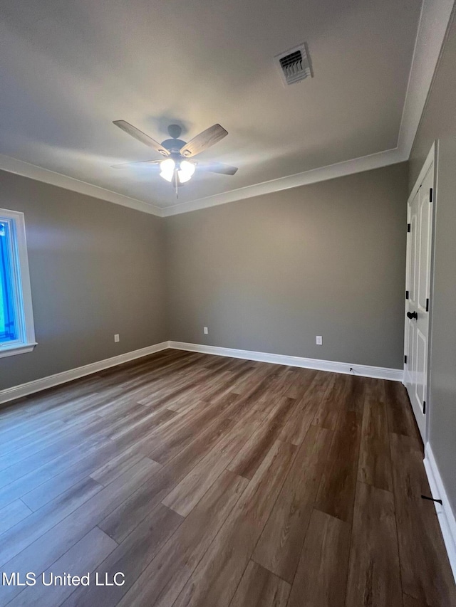 spare room featuring ceiling fan, ornamental molding, and dark wood-type flooring