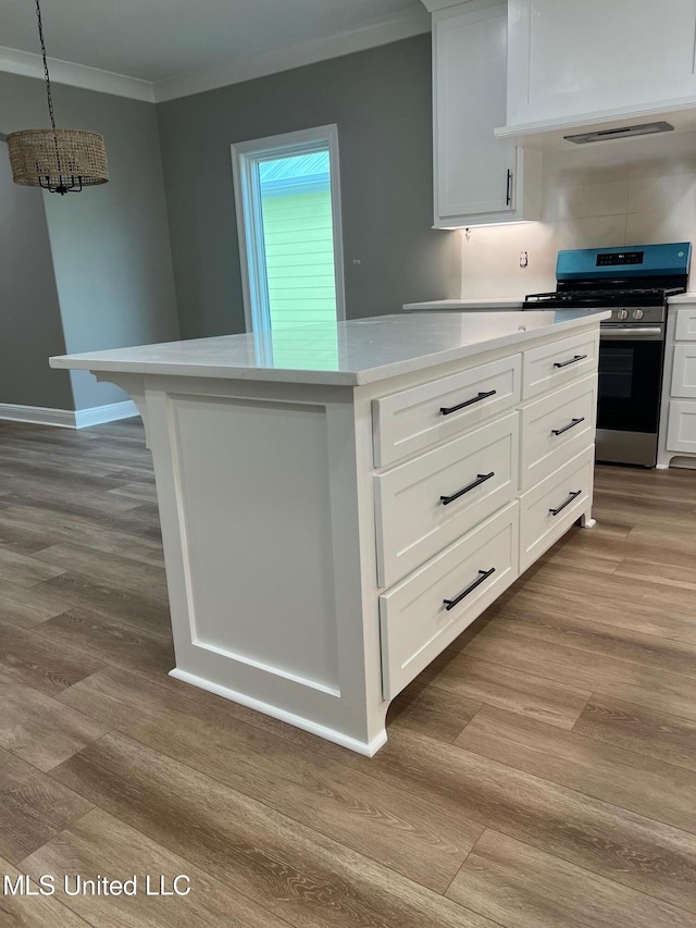 kitchen featuring white cabinets, decorative light fixtures, light hardwood / wood-style floors, and stainless steel range with gas stovetop