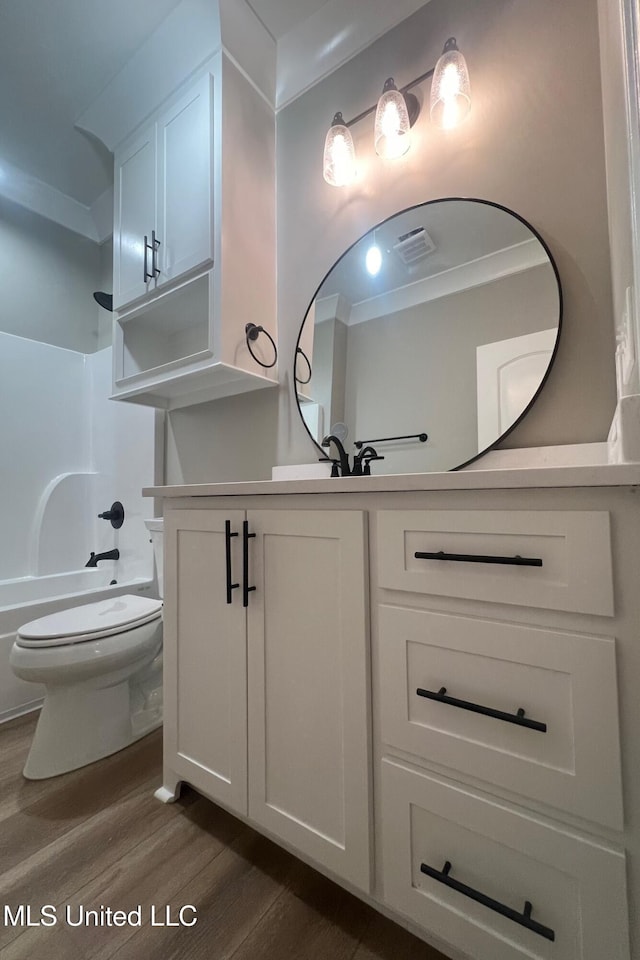 full bathroom with ornamental molding, bathtub / shower combination, vanity, hardwood / wood-style flooring, and toilet