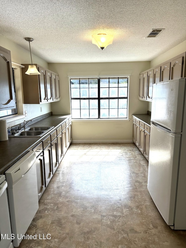 kitchen featuring white appliances, a textured ceiling, sink, and hanging light fixtures