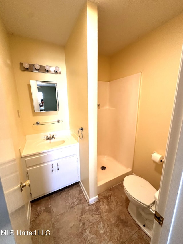 bathroom featuring vanity, a shower, and toilet