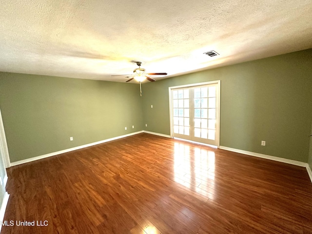 unfurnished room featuring dark wood-type flooring, ceiling fan, a textured ceiling, and french doors