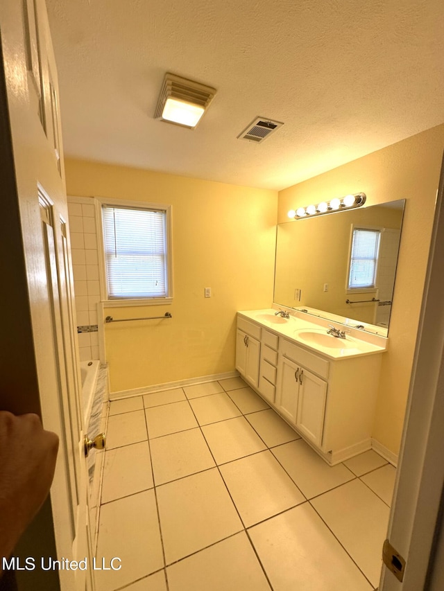 bathroom featuring vanity, a textured ceiling, a bath, and tile patterned flooring