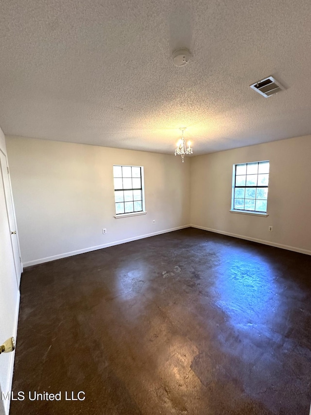 spare room with an inviting chandelier and a textured ceiling