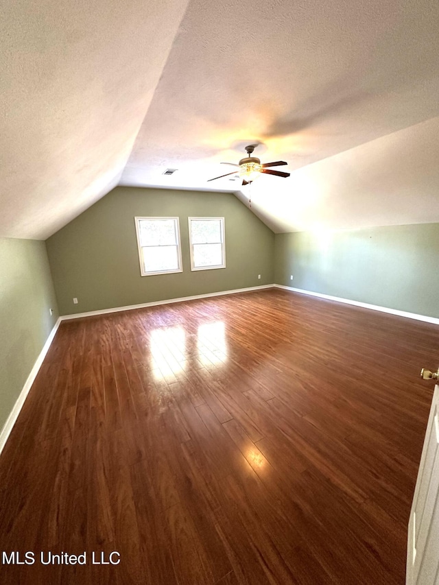 bonus room featuring a textured ceiling, vaulted ceiling, dark hardwood / wood-style floors, and ceiling fan