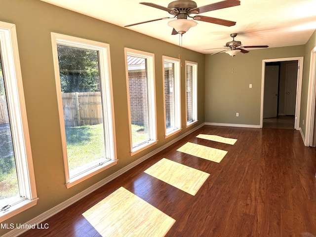 empty room featuring ceiling fan, dark wood-type flooring, and a wealth of natural light