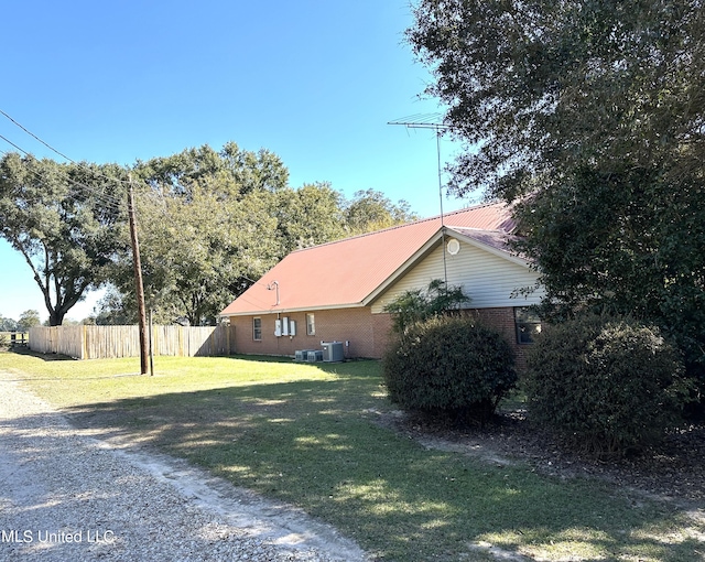 view of side of home featuring central AC and a lawn