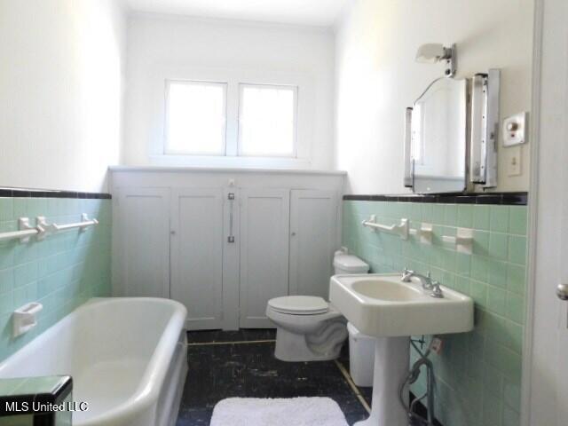 125 Riverside St, Vidalia, LA 71373 - full bath featuring a washtub, a wainscoted wall, tile walls, and toilet