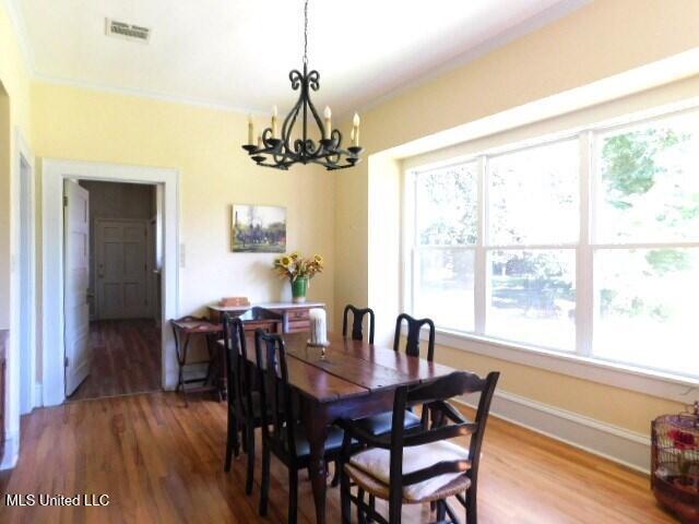125 Riverside St, Vidalia, LA 71373 - dining area featuring baseboards, visible vents, wood finished floors, an inviting chandelier, and crown molding
