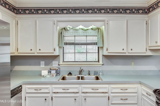 kitchen with appliances with stainless steel finishes, light countertops, a sink, and white cabinetry